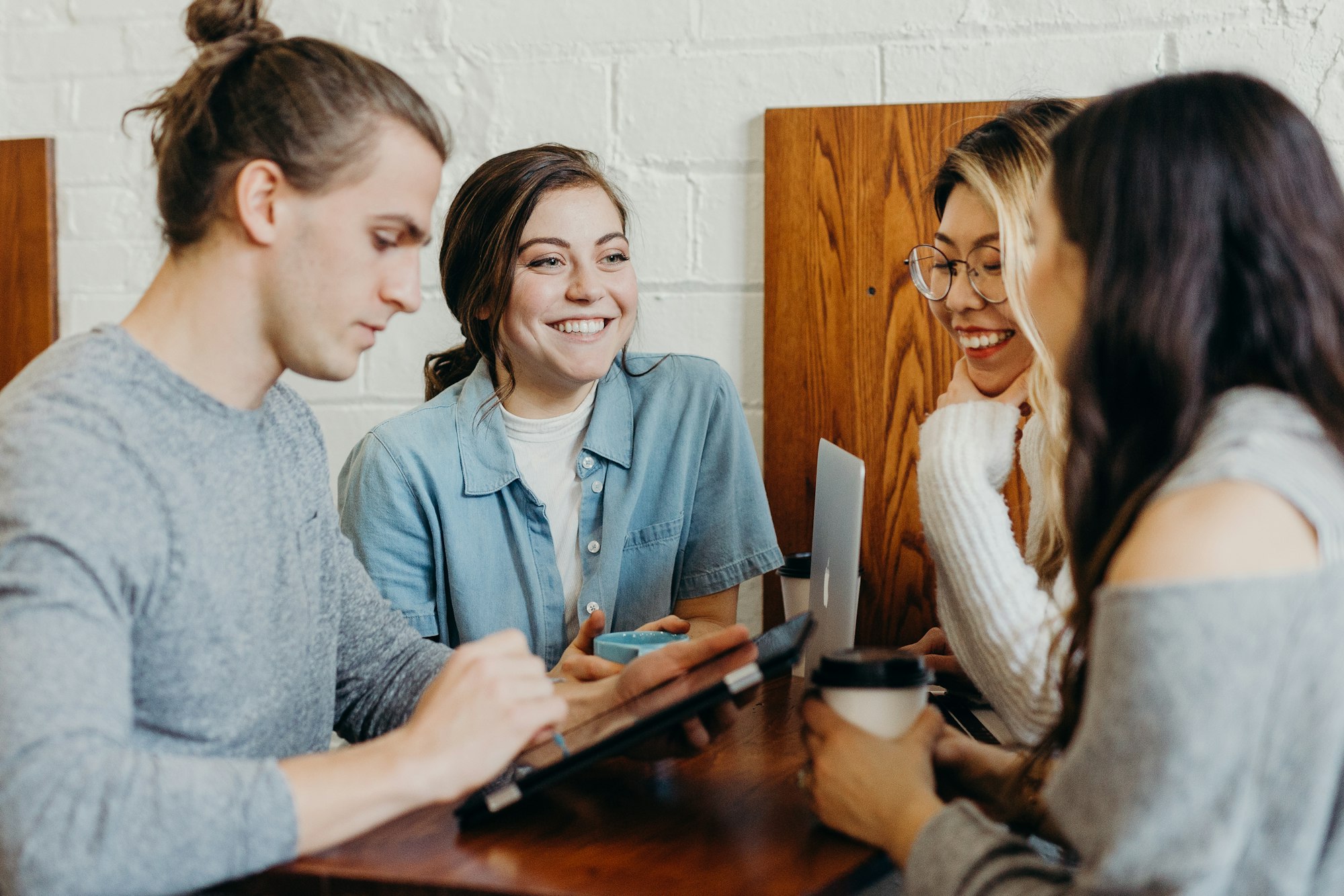 Four colleagues talking and laughing together around a café table